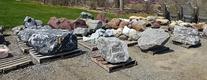 Rows of decorative boulders on pallets in the yard