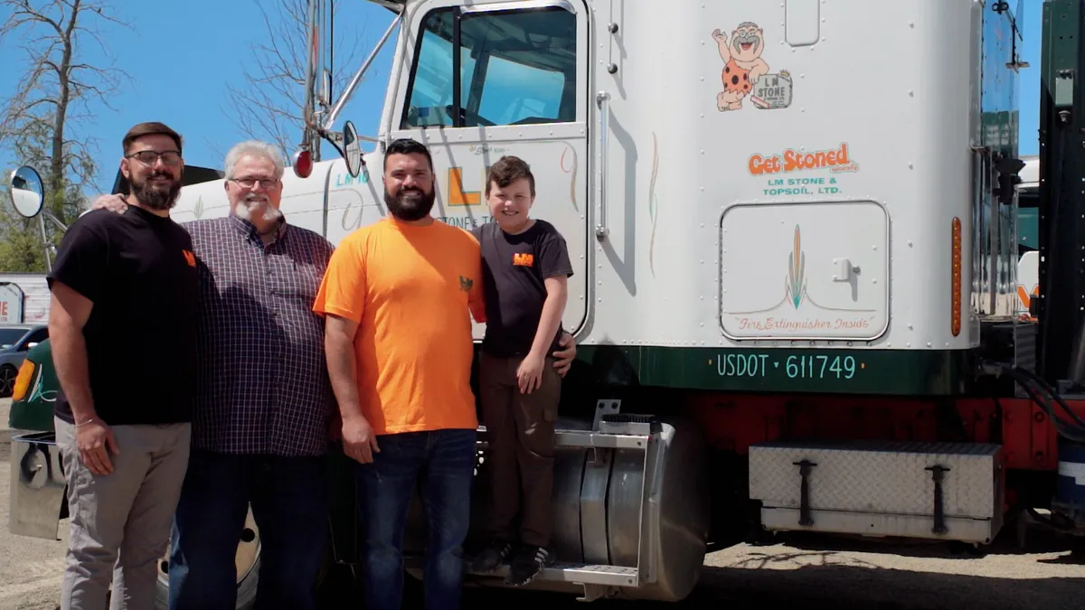 Three men and a boy in LM Stone shirts standing in front of a white LM Stone truck with the Stone King and Get Stoned logos on the door