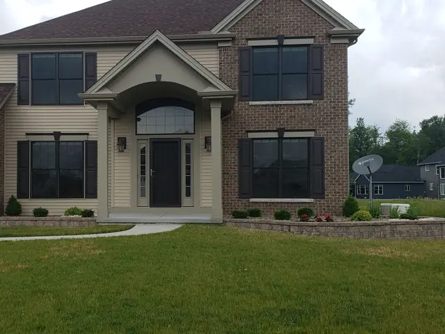 Mulched front beds edged with a low block wall in front of a two story house